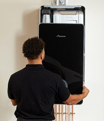 Engineer Fitting Black Worcester Boiler On Wall